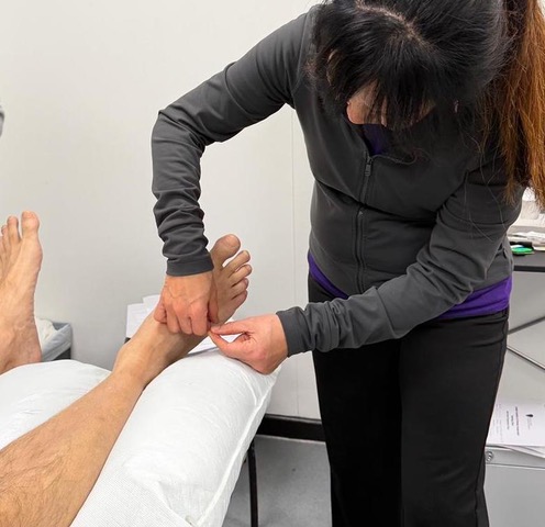 Emily Ho providing an individual acupuncture treatment